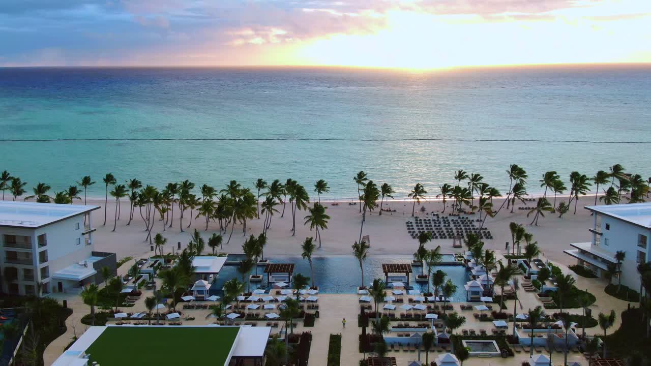 Alba su un resort tropicale sul mare, hotel di lusso con piscine e spiaggia di sabbia con palme al mattino, vista aerea di una destinazione di vacanza esclusiva nei Caraibi