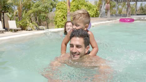 Glückliche-Kaukasische-Familie-Schwimmt-Mit-Schlauchbooten-Im-Schwimmbad