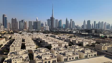 cinematic drone flight over suburb neighborhood in dubai city with epic skyline in background - beautiful sunny day with blue sky in uae