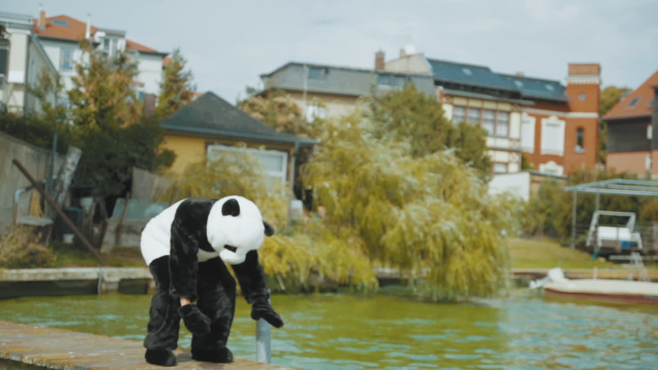 Campo lungo di un uomo in costume da panda che si allena su un pontile in un lago.