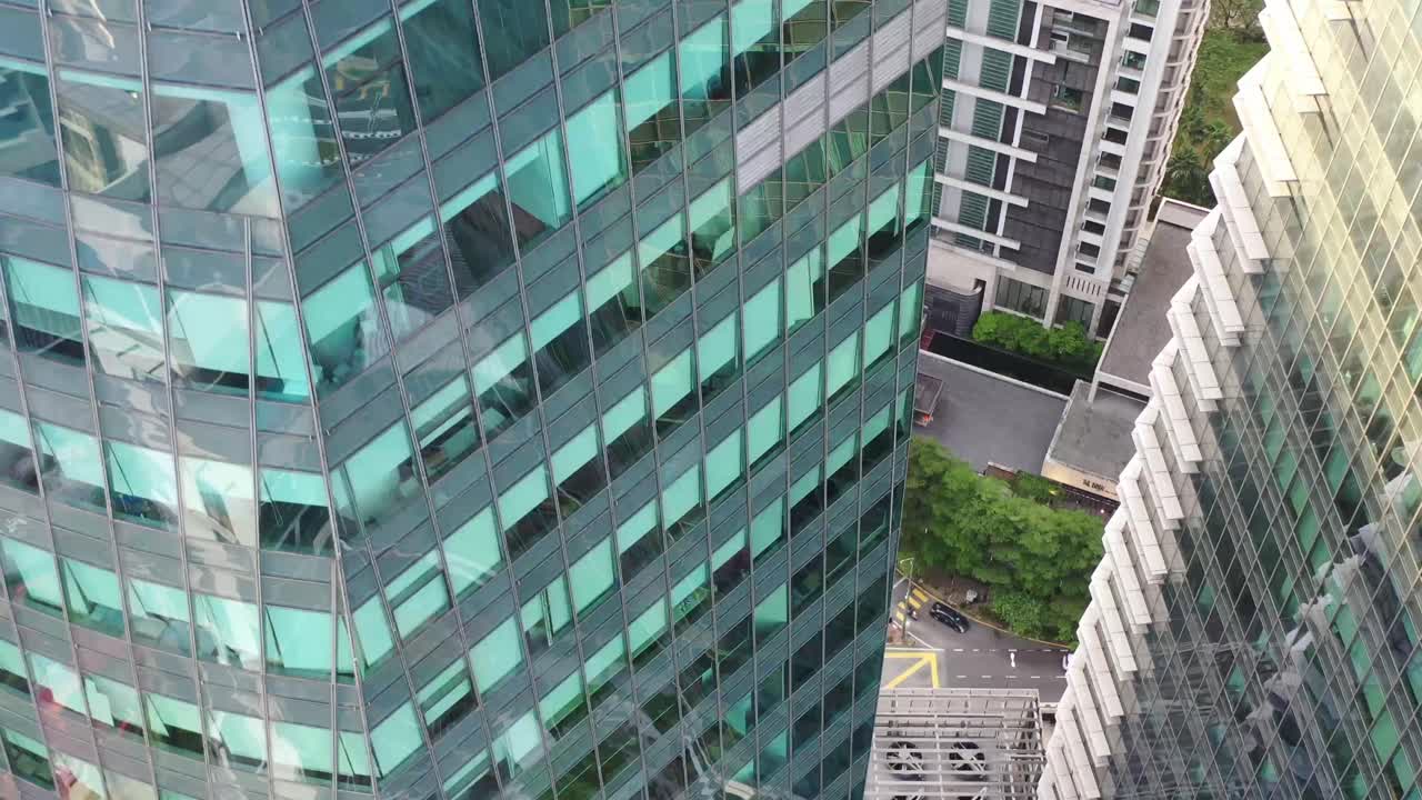 고층 빌딩 사이에 공중 받침대가 내려와 도심 지역의 유리창 정면이 있는 회사 사무실 건물의 클로즈업을 캡처합니다.