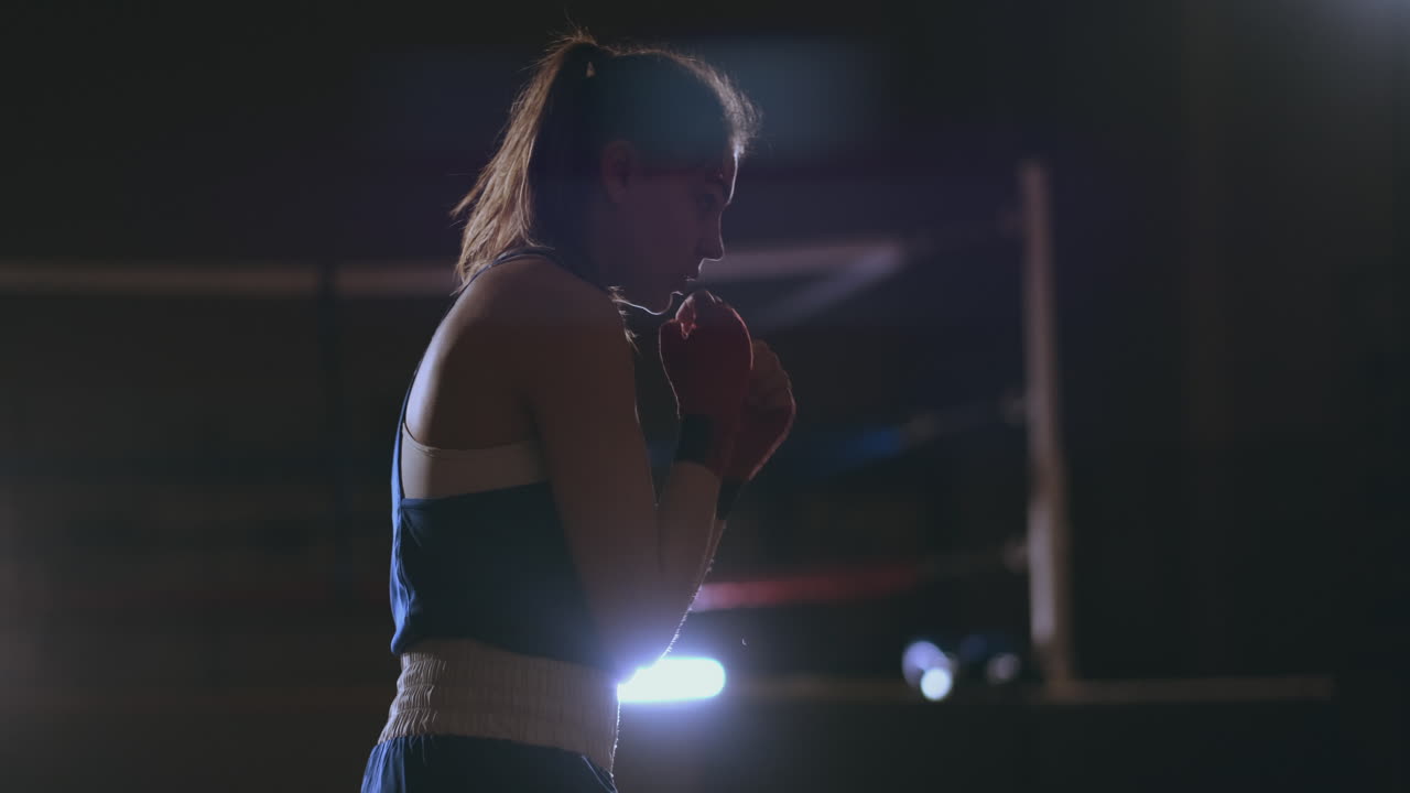 entrenamiento de boxeador femenino en una habitación oscura con luz de fondo en cámara lenta vista lateral. disparo de steadicam