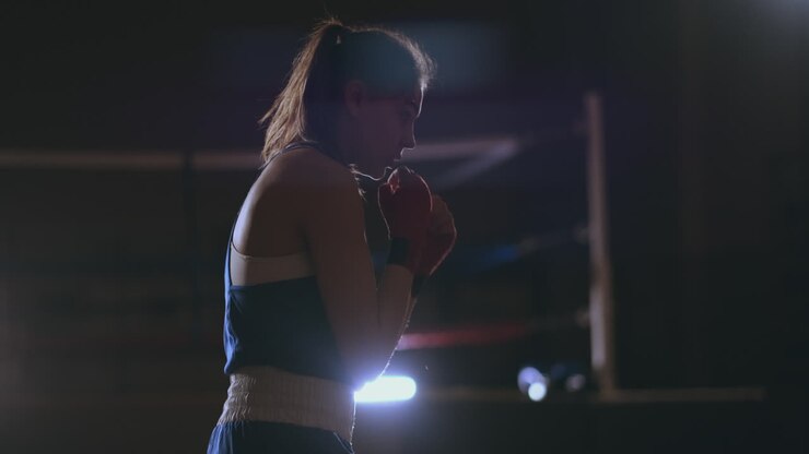 Female boxer training in dark room with backlight in slow motion side view. steadicam shot