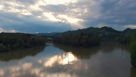 Schneller-Flug-Zum-Dramatischen-Sonnenuntergang-Mit-Sonnenstrahlen-über-Der-Drau-Bei-Maribor-Slowenien-Mit-Wald-Im-Hintergrund