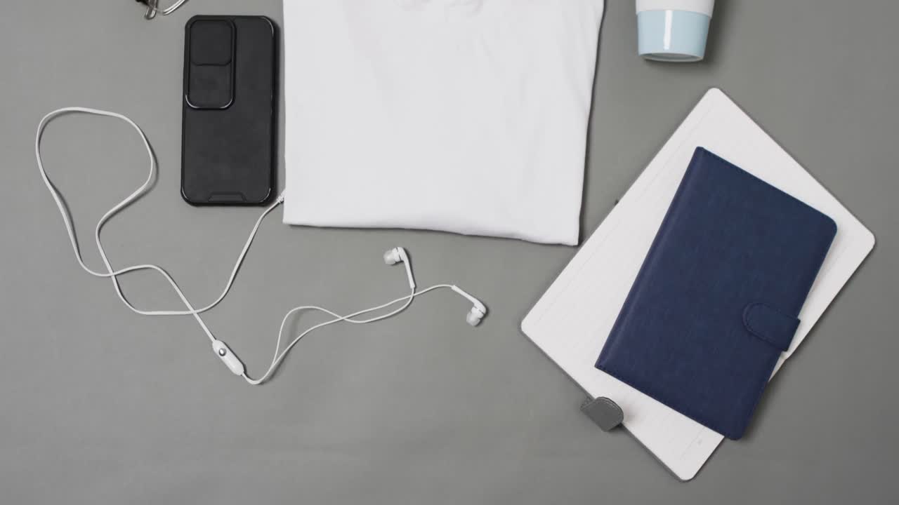 video de camiseta blanca, libretas, teléfono inteligente y auriculares con espacio de copia en fondo gris