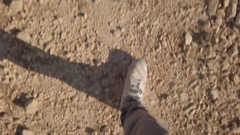 feet walking, hiking on desert ground of rocks and sand