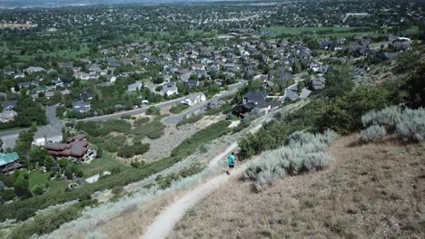 drone shot following an active man running on the outdoor mountain trails above draper city, utah-2