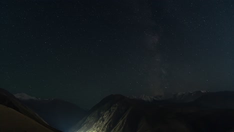 Night sky over mountainous landscape time lapse. Tian Shan mountain range. Stars and Milky Way visible in clear sky.