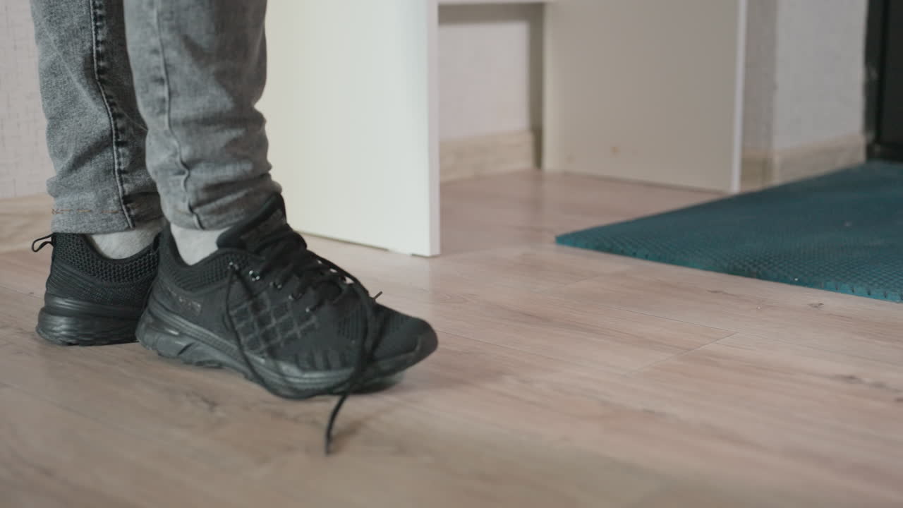 Black Sneaker Pause, Person Pauses With Sneaker, Individual Stops Near Apartment Doorway, Candid Moment Capturing Person In Jeans Pausing At Their Apartment Doorway With Casual Domestic Activity