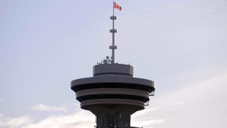 canadian flag waving on top of the harbour centre tower in vancouver