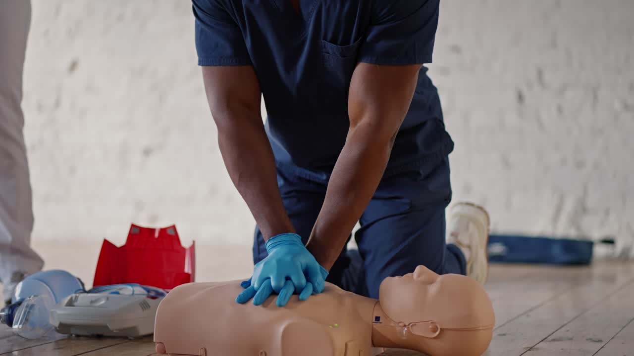 fotografía de cerca desde abajo: un médico profesional de raza negra lleva a cabo sesiones de práctica de atención médica, haciendo respiración artificial en un maniquí para el público