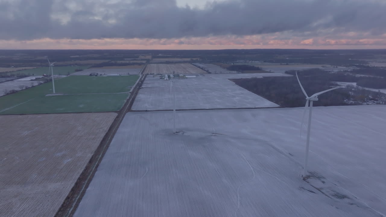 Winter landscape with wind turbines in frosty fields at dawn