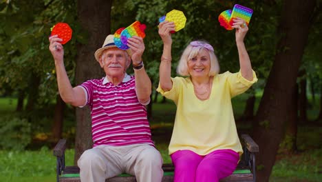 elegante abuela mayor abuelo sosteniendo apretando juguete anti-estrés juegos de hoyuelos simples en el parque
