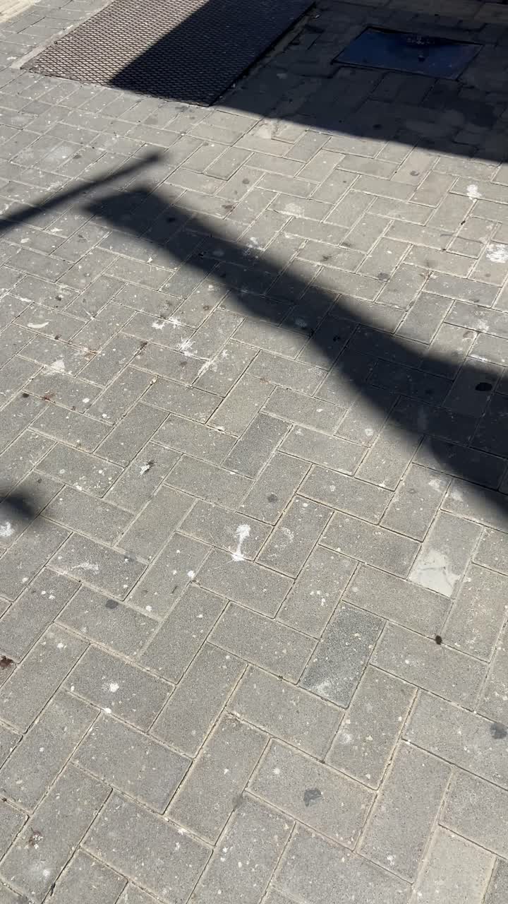 Shadow or silhouette on street of a flag on a pole blowing in wind and waving. Sunny day outdoors as flag moves in waves. Celebration or national independence holiday memorial day. Raising mast flag
