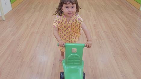 Happy-Excited-Child-Girl-Pushing-Toy-Car-From-Behind-And-Runs-Along-THe-Room---Tracking-Action-Front-view