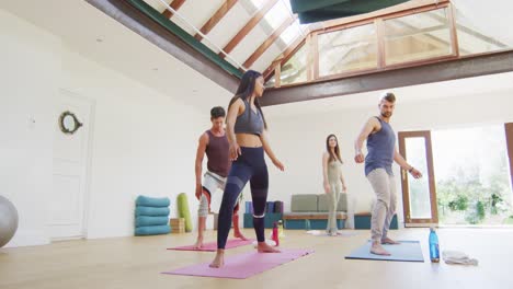 grupo diverso y instructora practicando yoga en clase en el estudio, con los brazos extendidos