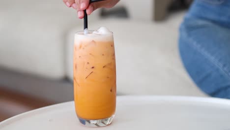 stirring a tall glass of iced tea on a table