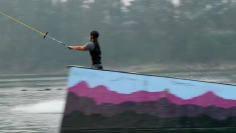 rear view of caucasian young man doing tricks on wakeboard in the city lake 4k