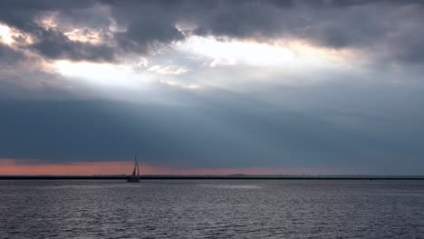 a sunset over lake erie with a sailboat sailing across the water
