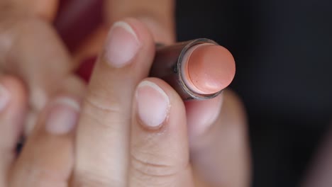 applying a light brown lipstick/blush