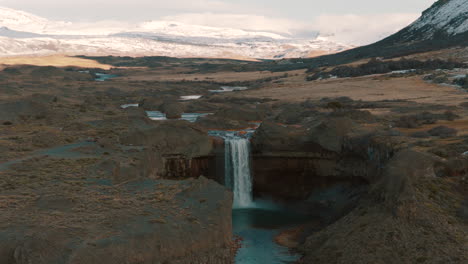 drone view of salto del agrio waterfall surrounded by volcanic cliffs and snowy andes mountains, caviahue, argentina