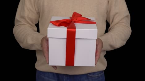 caucasian man in beige sweater is holding a white gift box in hands. white gift box with red ribbon bow. front view of man in casual beige sweater. man gives a gift. alpha channel chroma key.