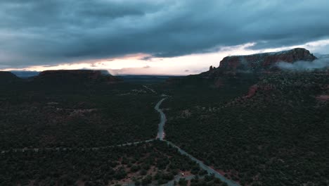 red rock state park with road through green trees in sedona, arizona on a cloudy day - aerial drone shot