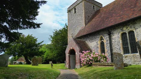 A-push-in-shot-towards-the-entrance-of-St-Margaret-of-Antioch-church,-following-the-path-along-the-graveyard