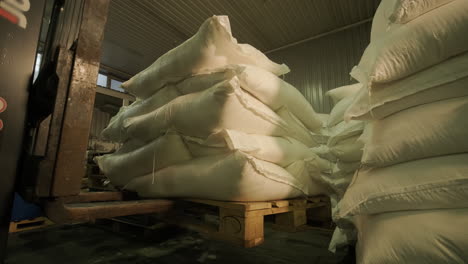 forklift loading pallets of grain bags in warehouse