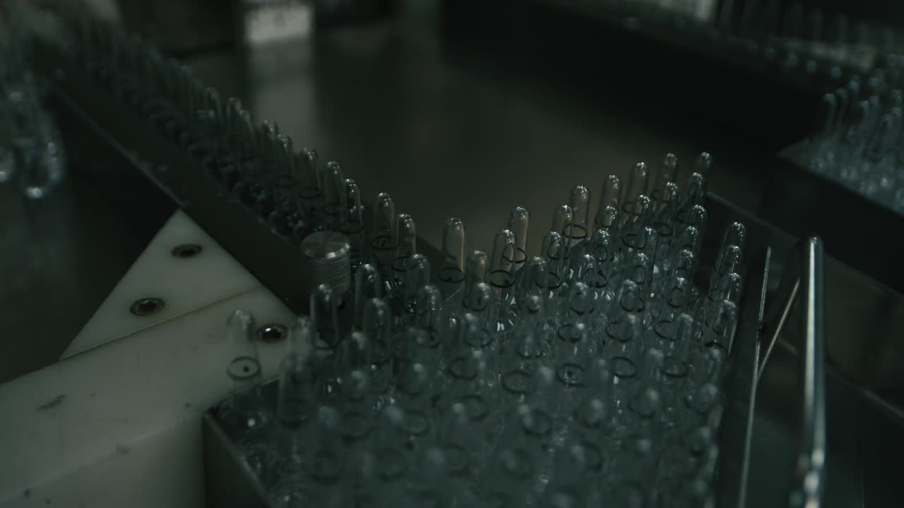 A row of clear plastic bottles are being filled with liquid in a bottling factory being organized on the conveyor to be filled up with the bottling machine on a large factory of industry