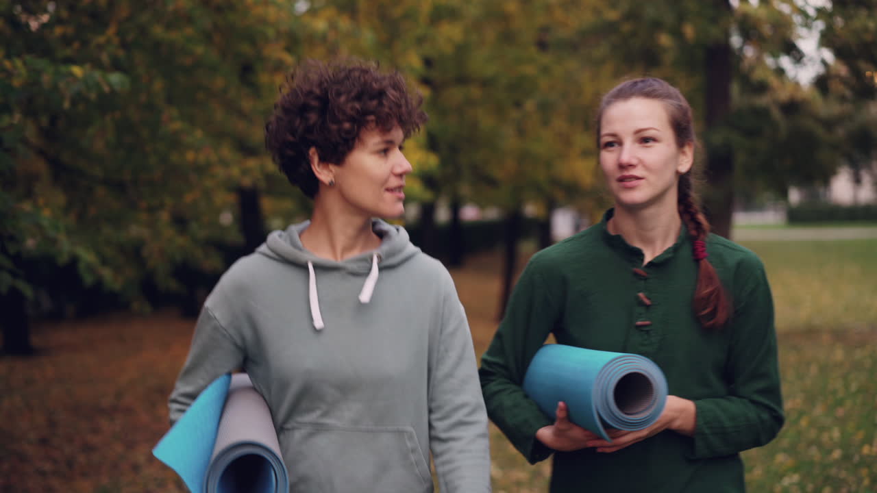 Two Women Walking in Park with Yoga Mats