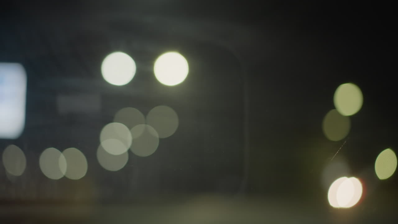luzes borradas da cidade em bokeh, halos suaves e faróis desfocados, vista do para-brisa com brilho do painel, banho de cor de outdoor, tráfego em movimento renderizado como círculos, clima de fotógrafo, sonho cinematográfico