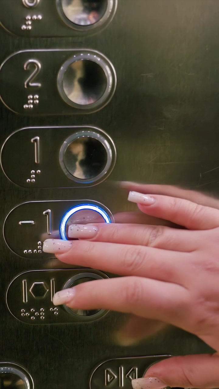 Primo piano della mano di una donna con unghie curate. La sequenza mostra movimenti e interazioni deliberate mentre ogni pulsante viene premuto. L'illuminazione soffusa crea riflessi su superfici metalliche