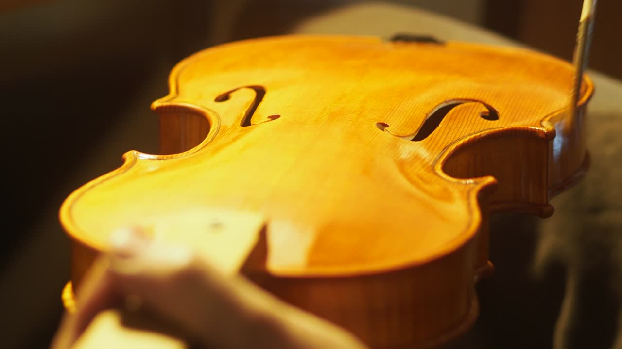 mano de un luthier fabricante de violines barnizando un instrumento de cuerda de madera hecho a mano