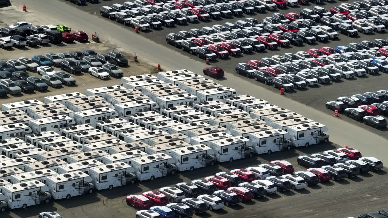 カナダ、BC州リッチモンドにある、輸入されたRV車や自動車が並ぶ大規模車両置場の空撮。後退、ティルトアップショット。