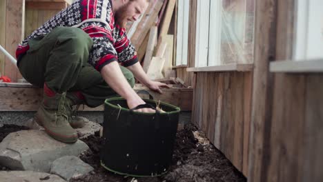 hombre poniendo virutas de madera seca en el piso del invernadero