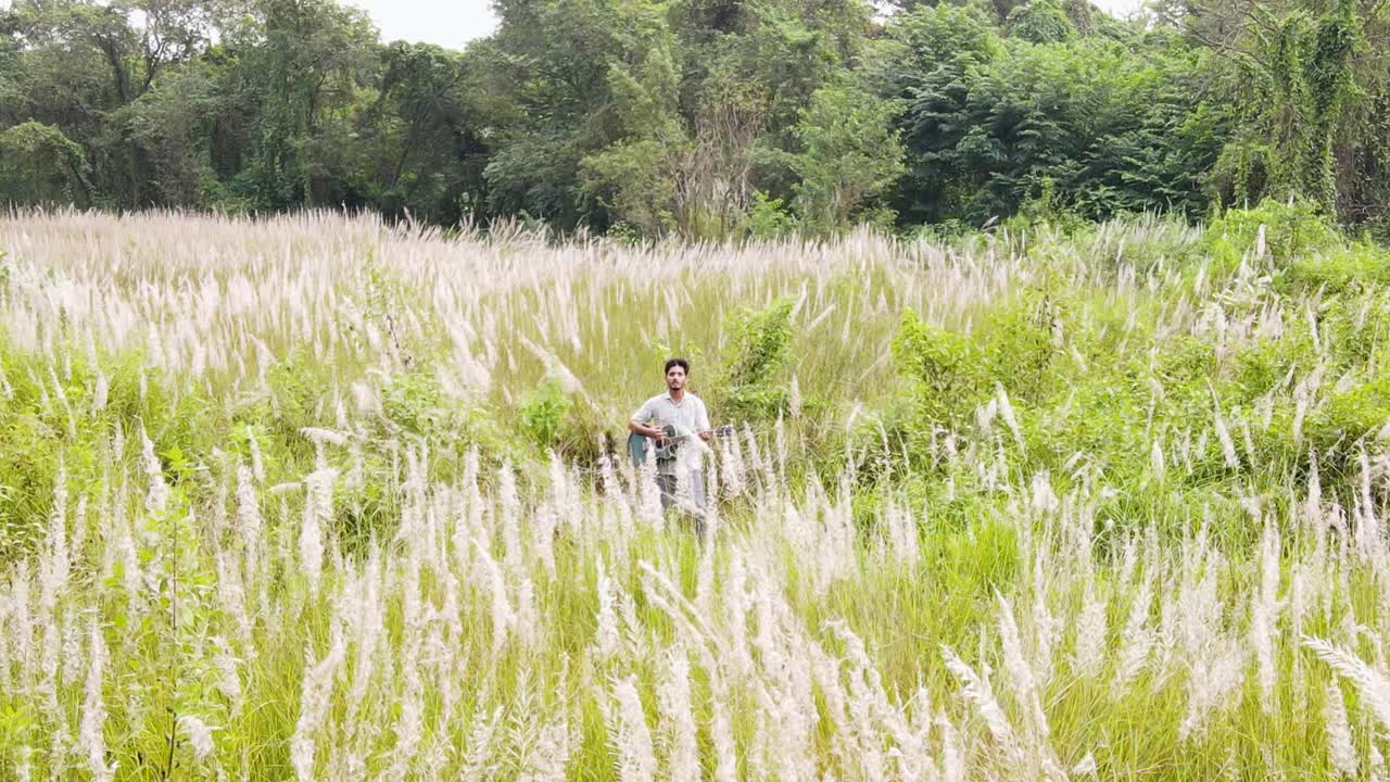 Man Plays The Guitar In A Field Of Kashful - Pullback