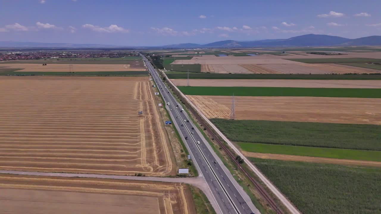 Scenic footage of traffic on the E574 road, with a car moving through a rural agricultural area near Brașov