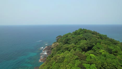 flying over the lush green grove on bom bom island towards the sea with a boat riding in the beautiful african sea. ilha do principe (prince island) africa