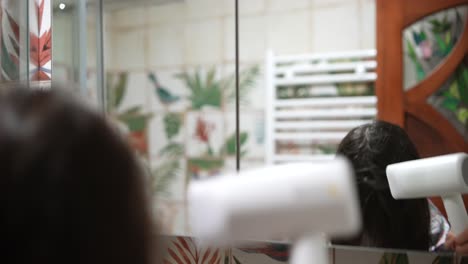 mujer secándose el cabello en el baño