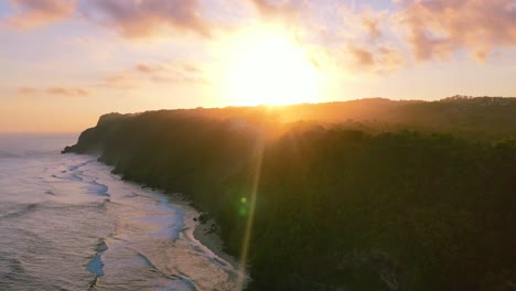 aerial coastline of ocean waves crashing on uluwatu cliffs at sunset in bali indonesia