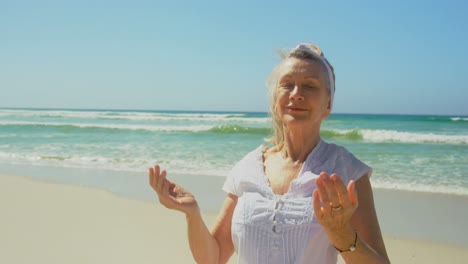 Vista-Frontal-De-Una-Mujer-Caucásica-Senior-Activa-Realizando-Yoga-En-La-Playa-4k