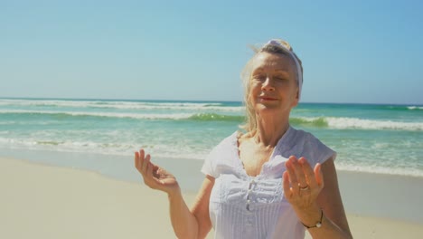 vista frontal de una mujer caucásica senior activa realizando yoga en la playa 4k