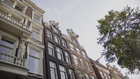 low angle view of beautiful canal-side houses with lifting beams located on the wallen in amsterdam, the netherlands