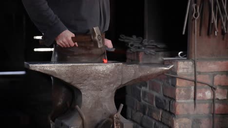 blacksmith hammering metal at anvil in workshop