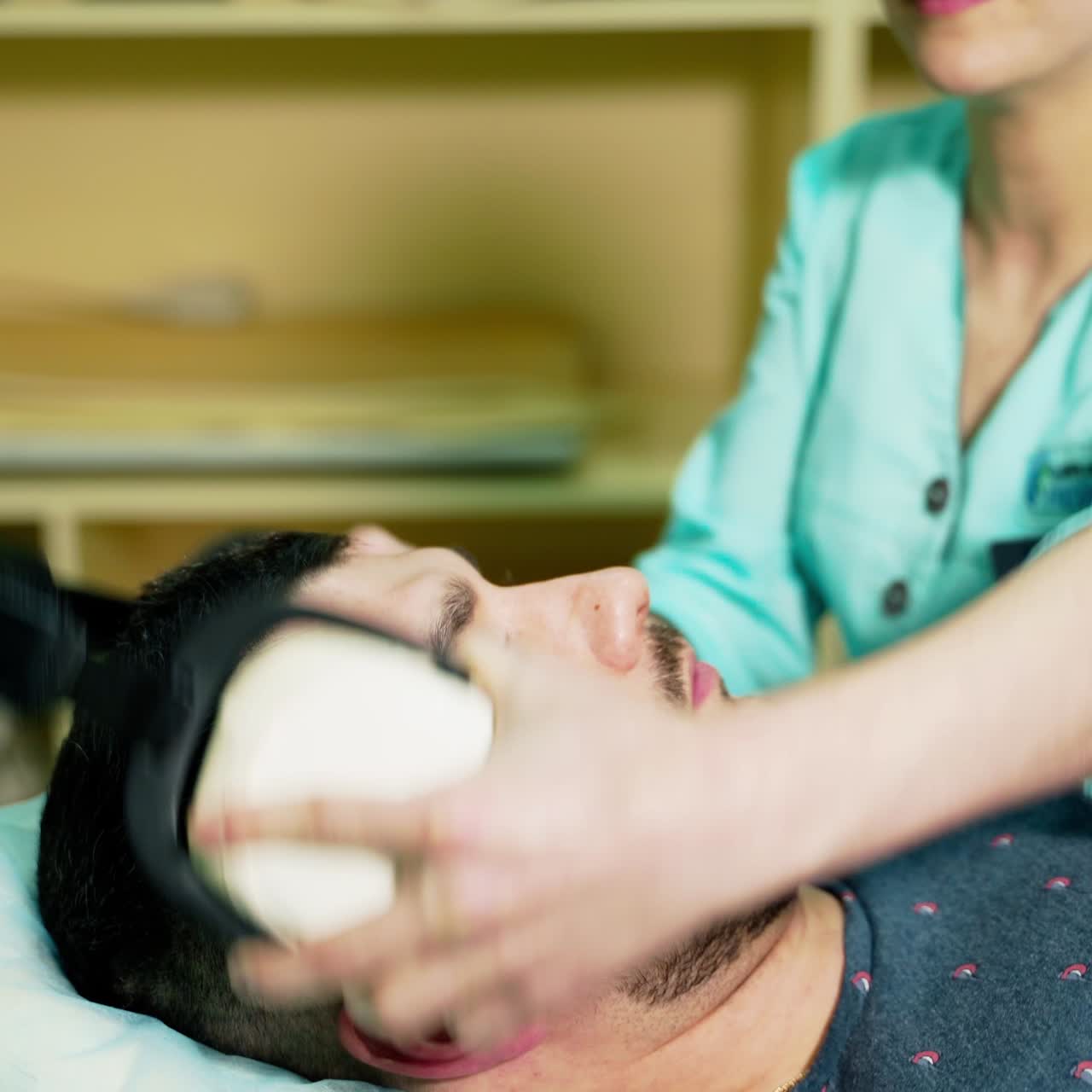 Medical worker and a male patient in clinic. Nurse puts on headphones to the sick patient. Healthcare concept.