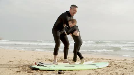 father and son with surfboards on beach