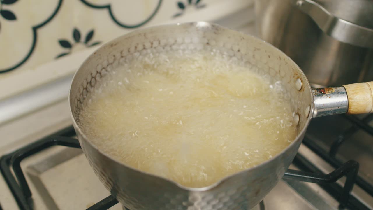 Chef puts chicken meat into pot with hot boiling oil