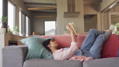 Video-De-Una-Mujer-Birracial-Recostada-En-Un-Sofá-Y-Leyendo-Un-Libro