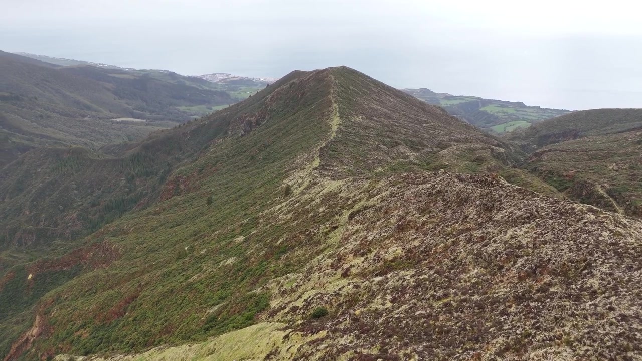 Volo panoramico aereo sopra una stretta cresta montuosa e le pareti del cratere nel complesso vulcanico di Lagoa do Fogo sull'isola di São Miguel, Azzorre